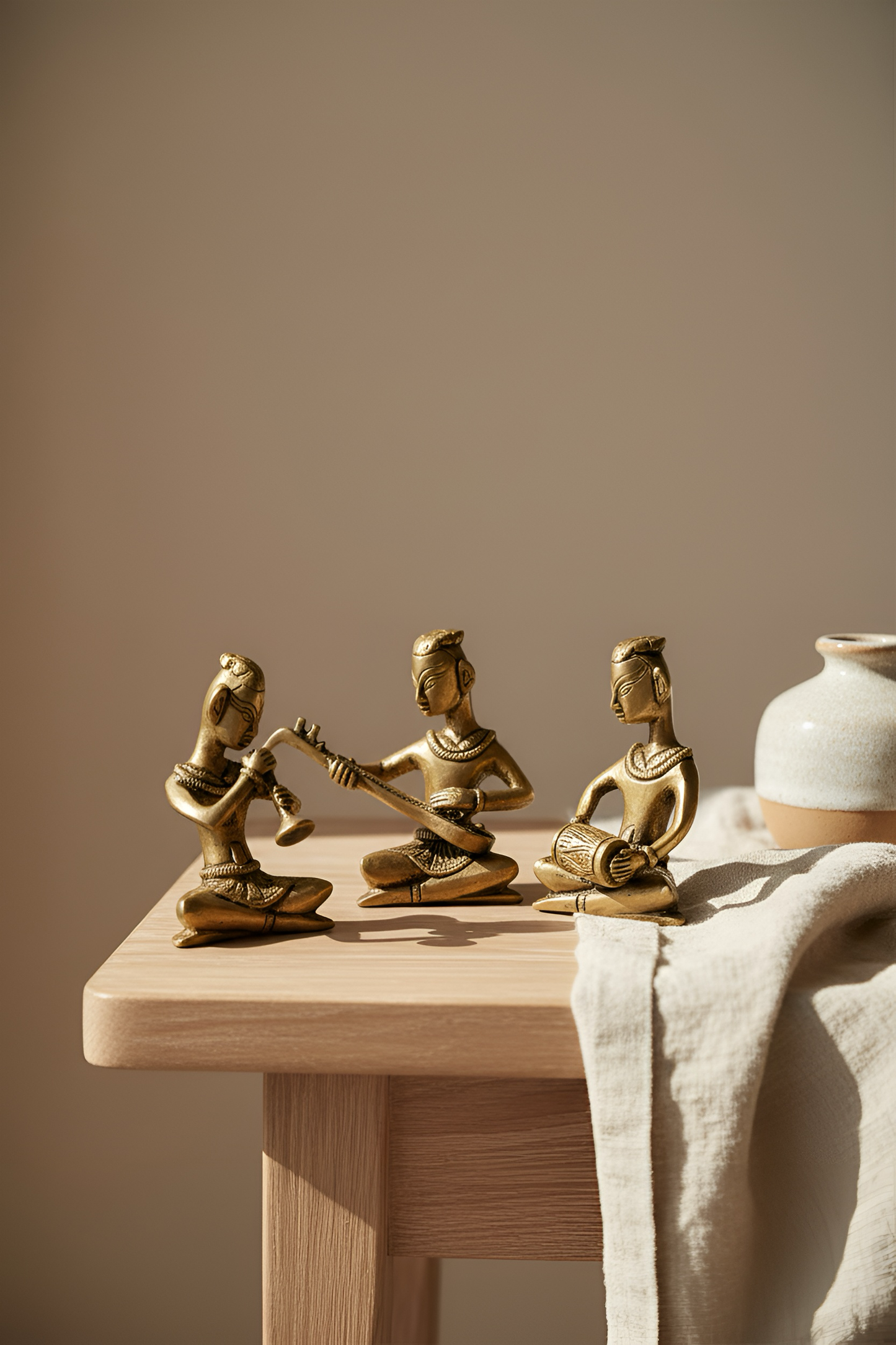 Three gold figurines on a wooden surface with a neutral background