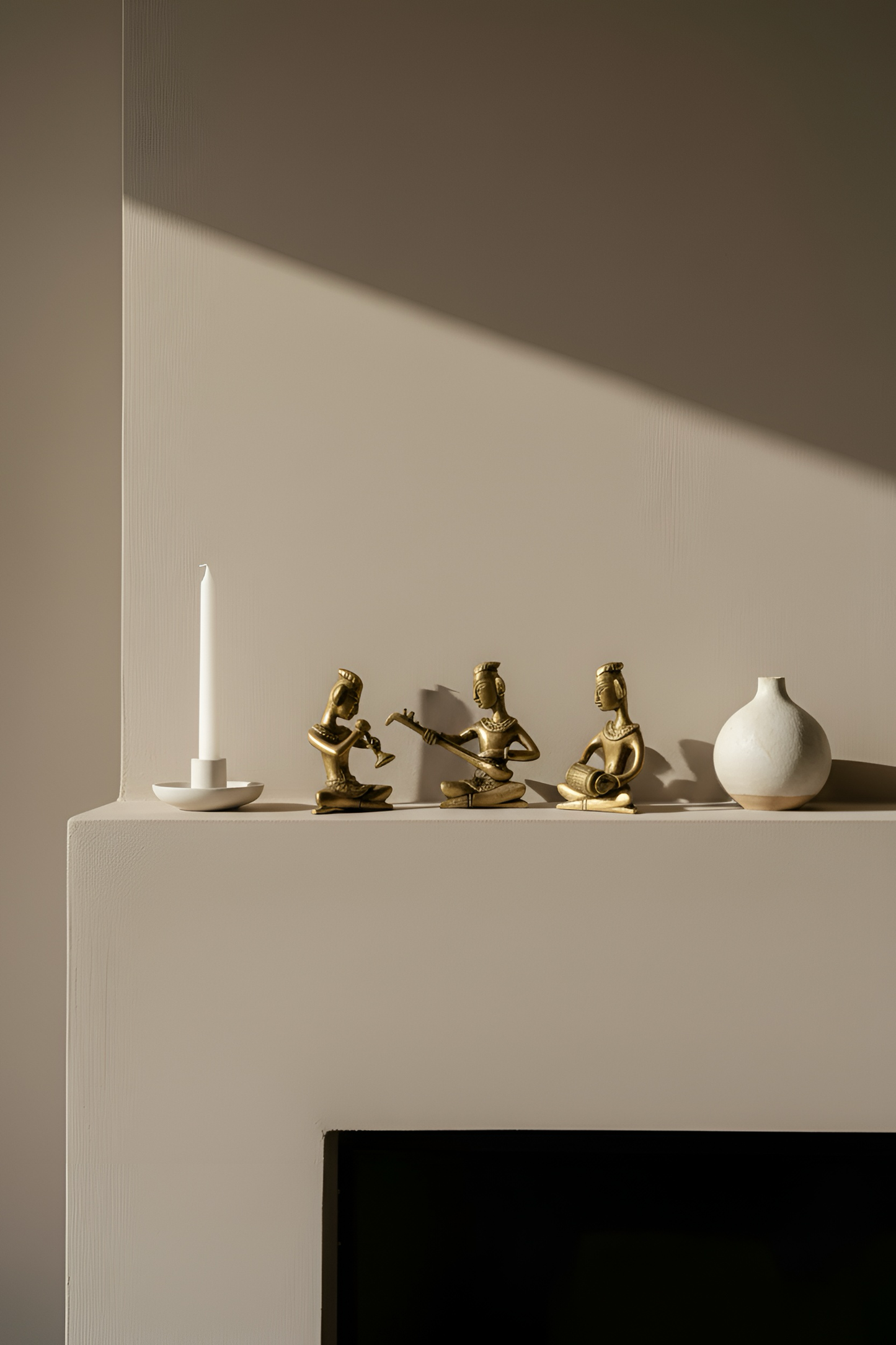 Decorative items including a candle, statues, and a vase on a shelf against a neutral wall.