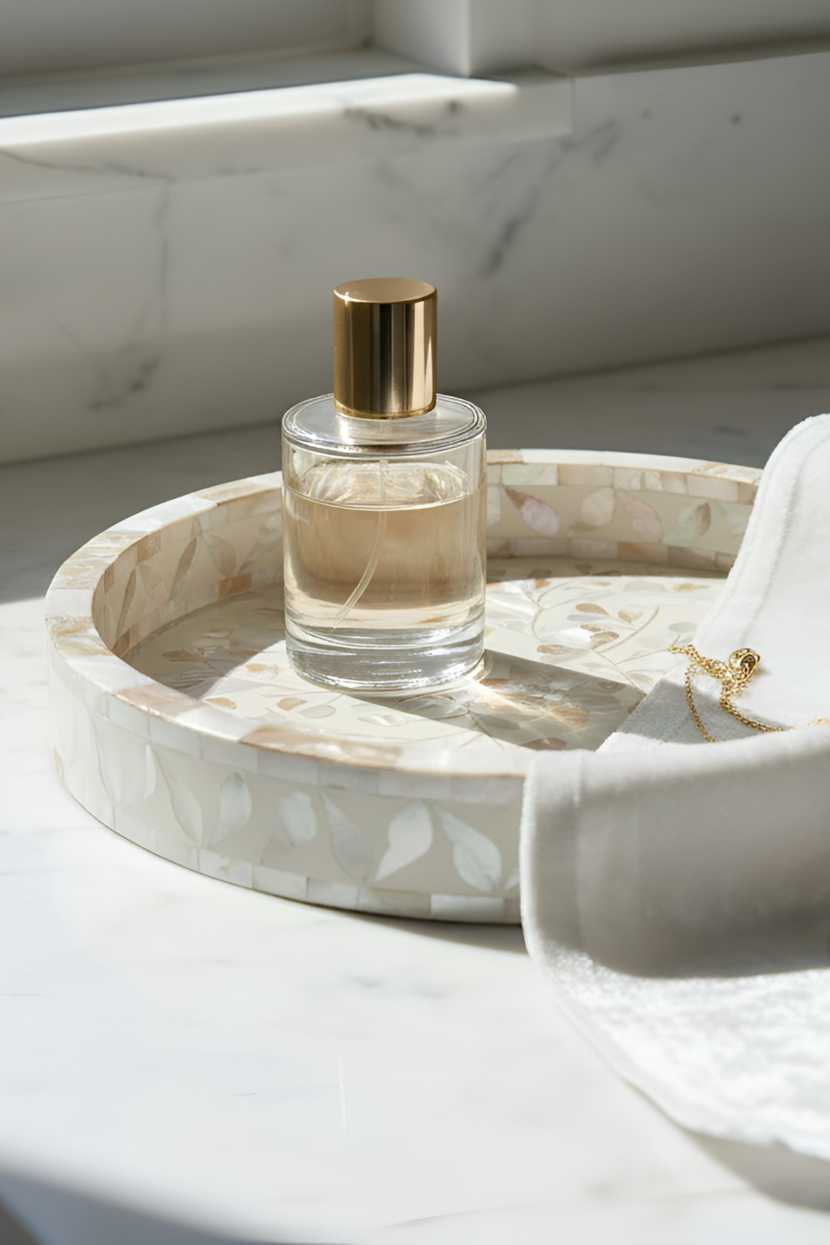 Perfume bottle on a decorative tray with jewelry on a marble surface